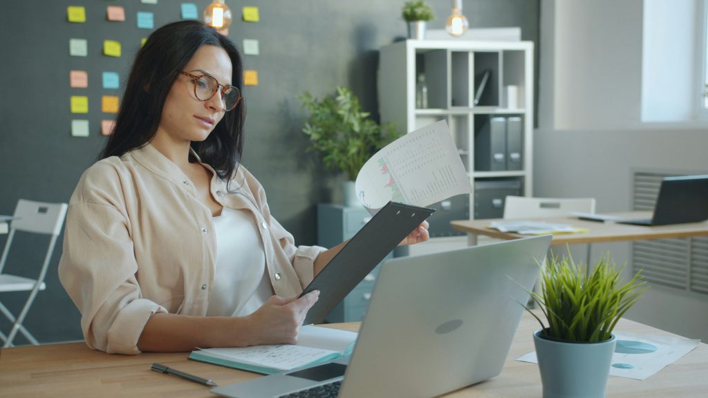 Office worker reviewing a document and laptop