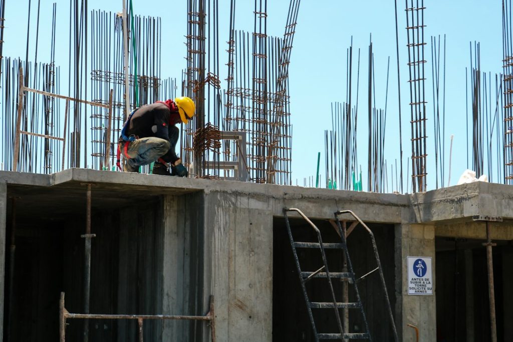 Bouwvakker met helm en harnas op de ruwbouw van een gebouw