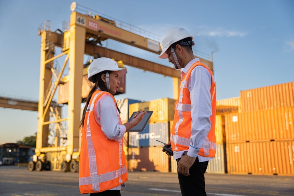 Twee havenmedewerkers met helm bij containers