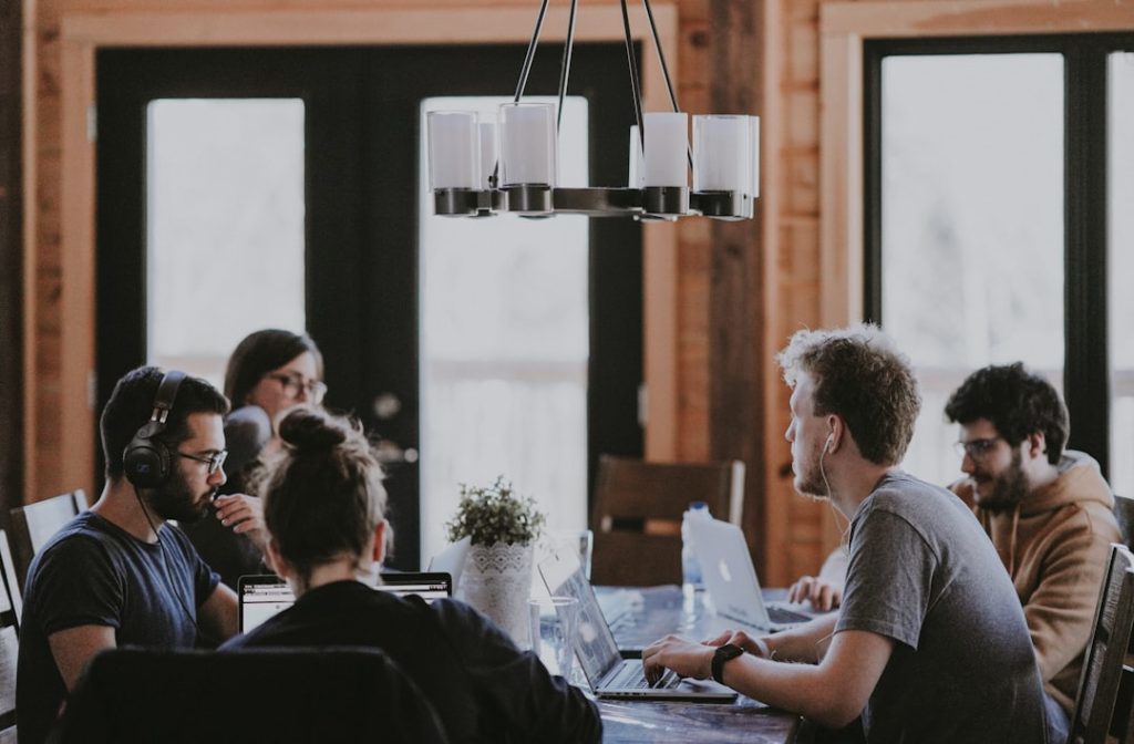 Collega's werken samen aan laptops rond een tafel