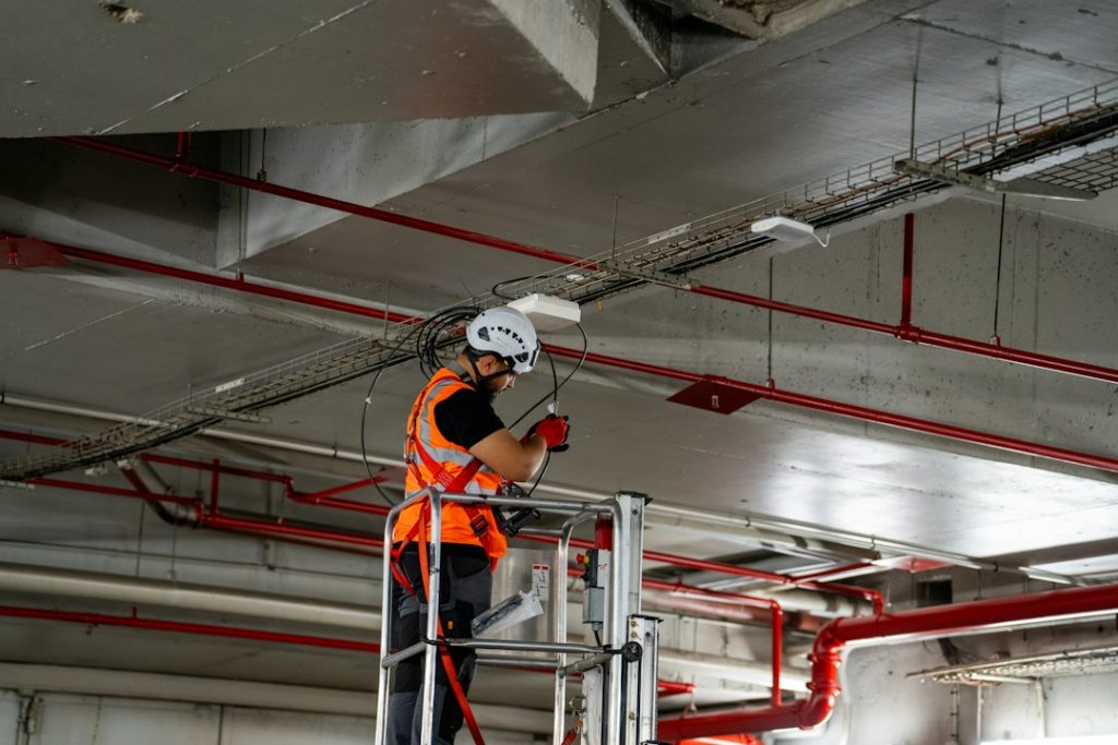Bouwvakker op hoogwerker installeert plafondonderdelen