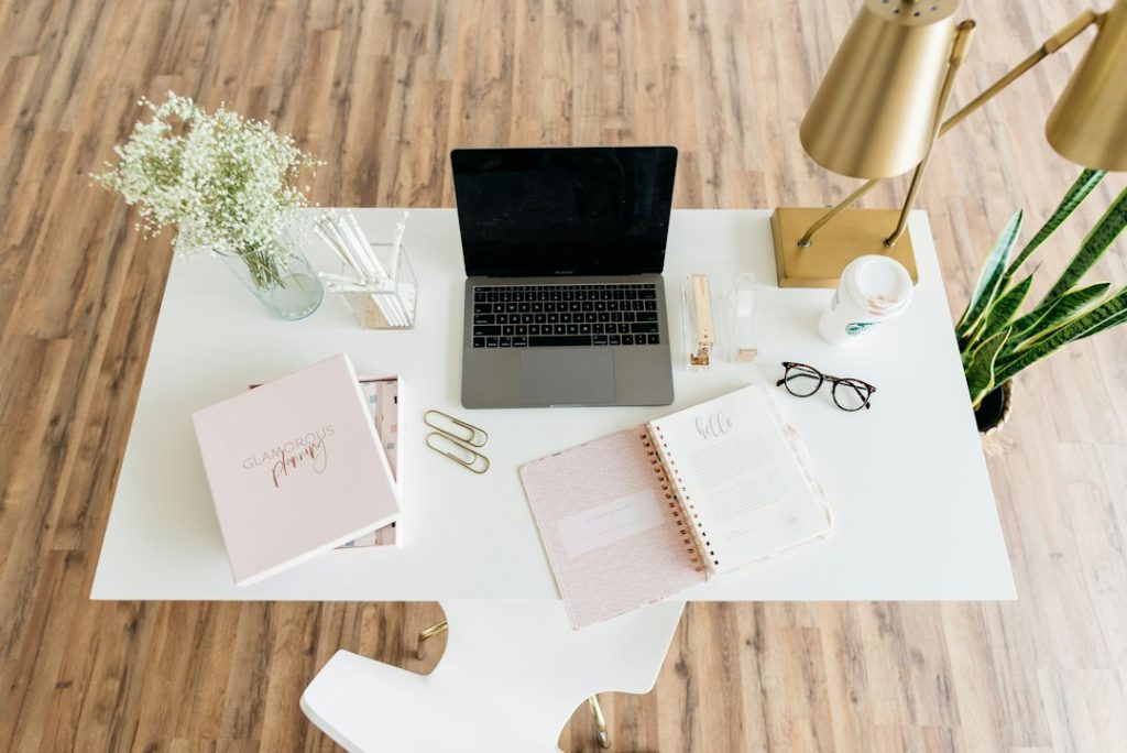 Thuiswerkplek met laptop en notitieboeken op een wit bureau