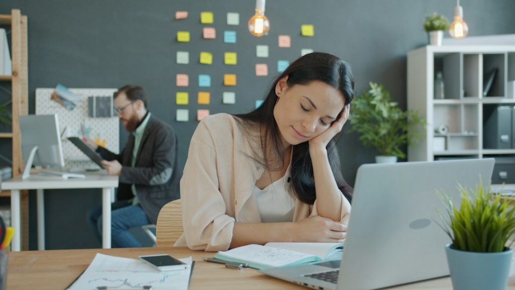Vermoeide vrouw achter haar laptop op kantoor