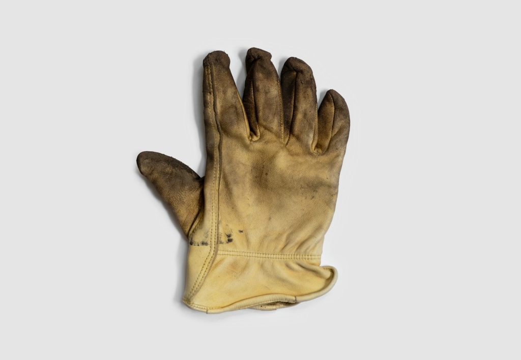 Used leather work glove against a light background