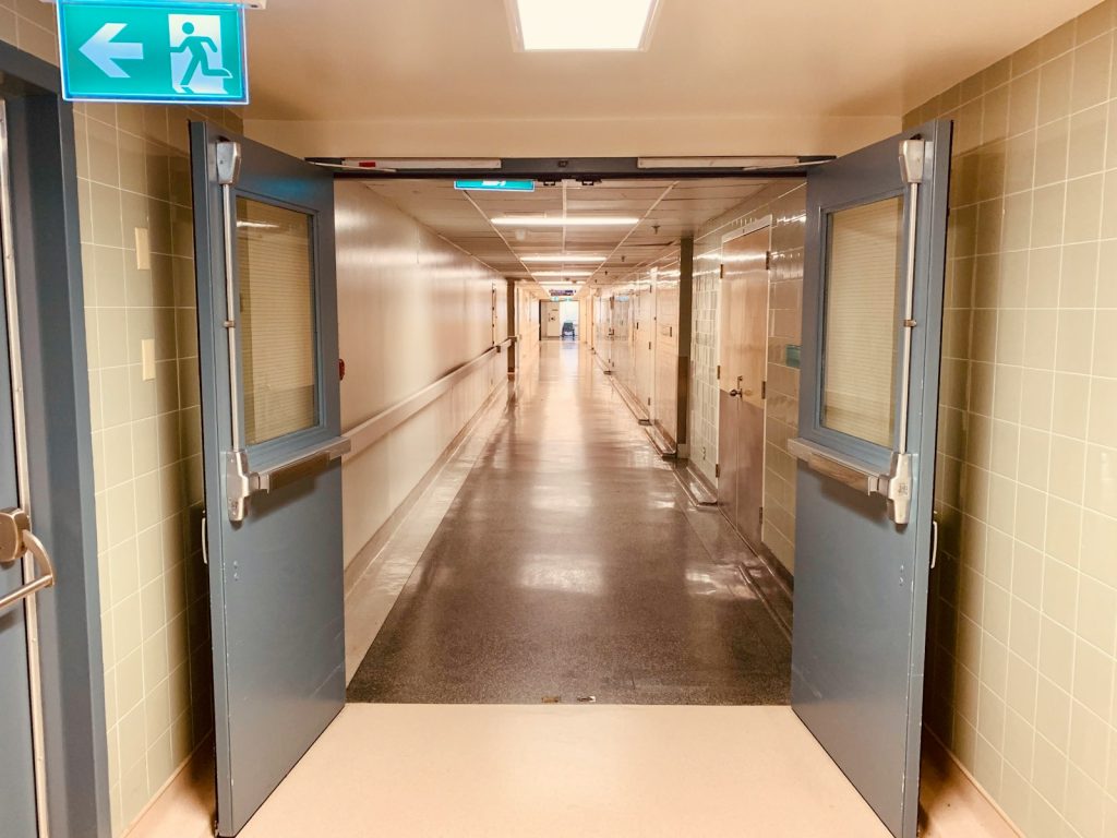 Lange, lege ziekenhuisgang met open dubbele deuren