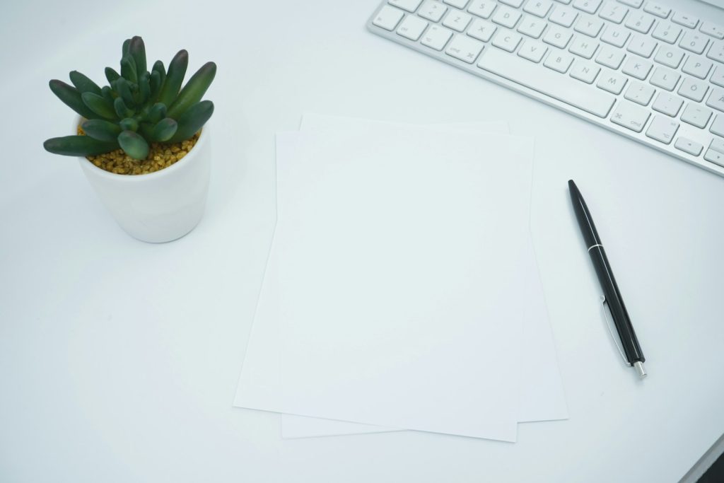 Stapel papieren op een kantoorbureau naast pen en toetsenbord, symbool voor administratieve rompslomp