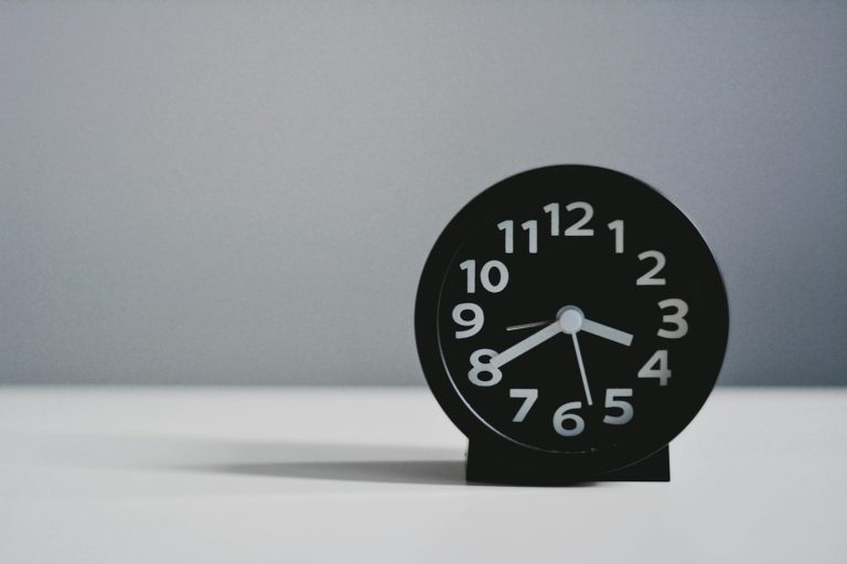 Minimalist black alarm clock on a desk, symbolising time pressure at work