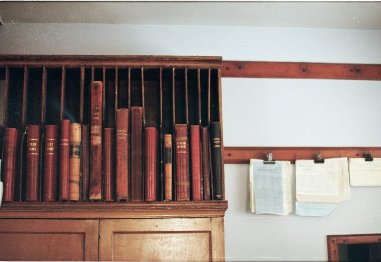 Wooden bookshelf filled with antique books.