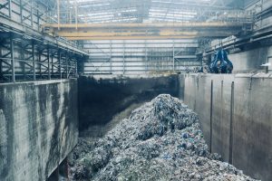 Workers sorting packaging waste on a conveyor belt in an industrial sorting hall