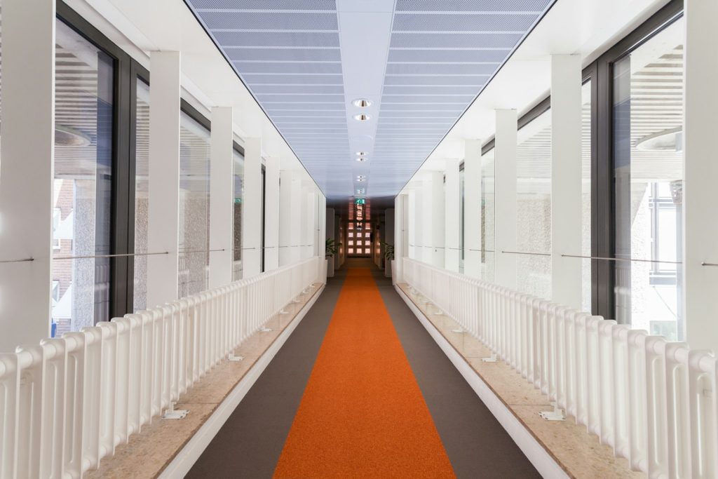 Empty glass corridor with white railing between buildings