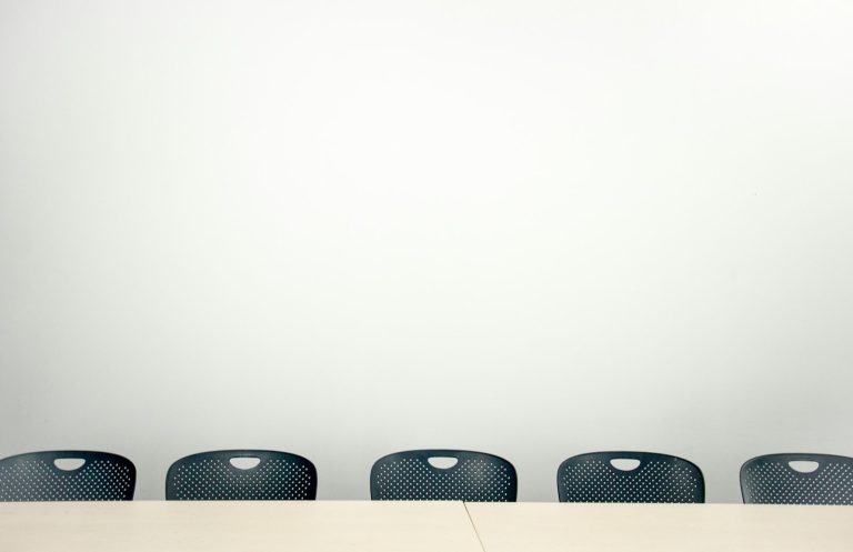 Gruppe von Kollegen im Gespräch an einem Tisch im Büro, Symbol für die Zusammenarbeit an einem gesunden psychosozialen Arbeitsumfeld