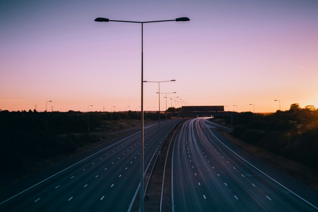 Empty highway with light poles at dusk