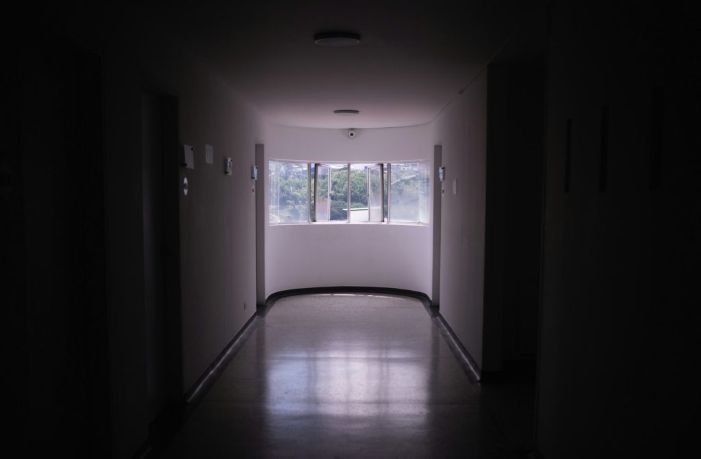 Empty hospital corridor at night with dim light and a view of a window