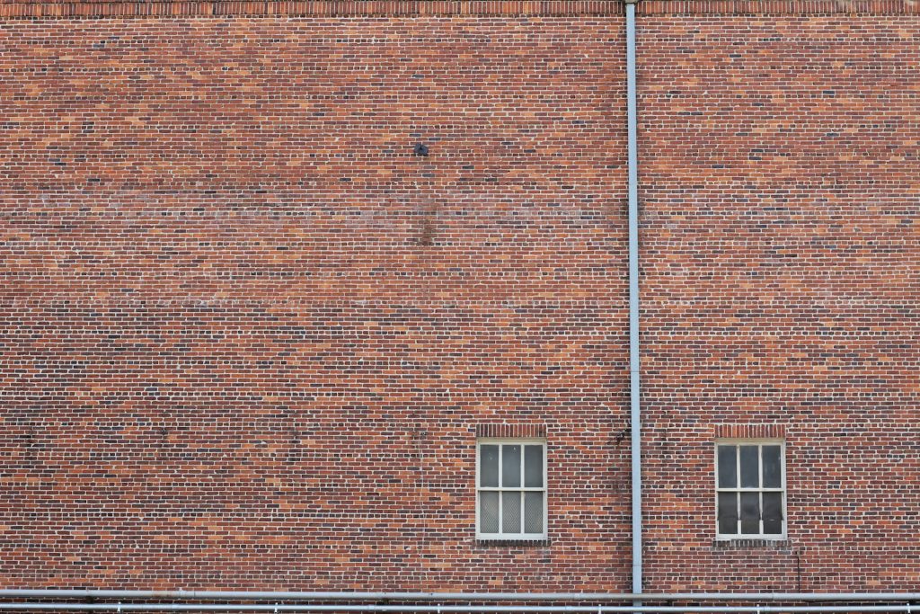 Close-up of a weathered old brick facade with two windows