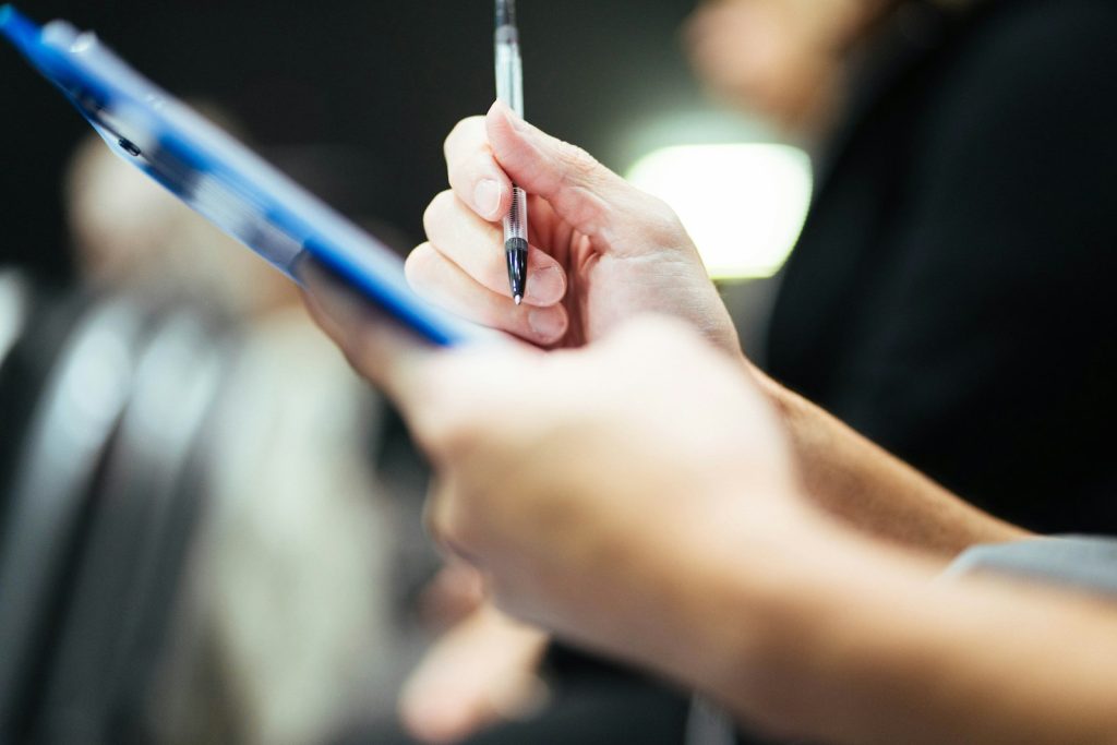 Main tenant un stylo au-dessus d'un porte-bloc bleu avec une liste de contrôle